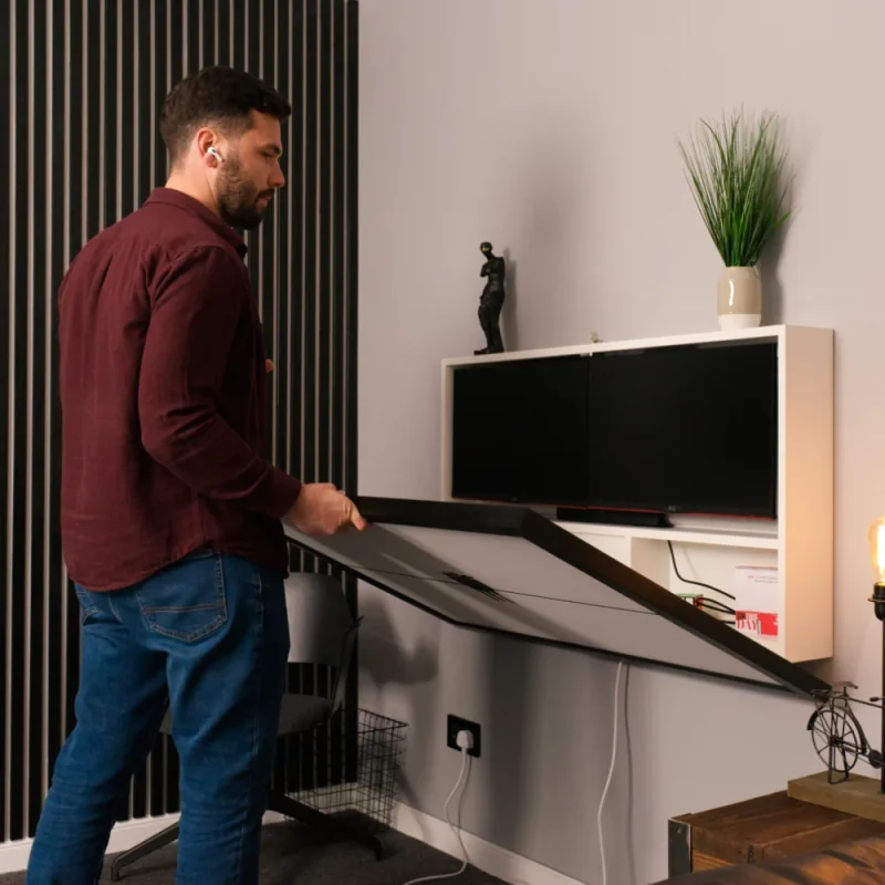 Man folding away his wall mounted hideaway desk.