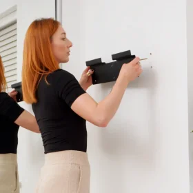 Lady installing a bracket for a wall mounted fold out desk.